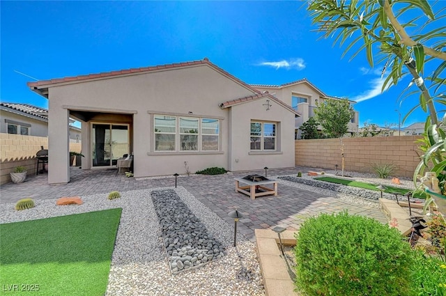 back of property featuring an outdoor fire pit, a patio area, a fenced backyard, and stucco siding