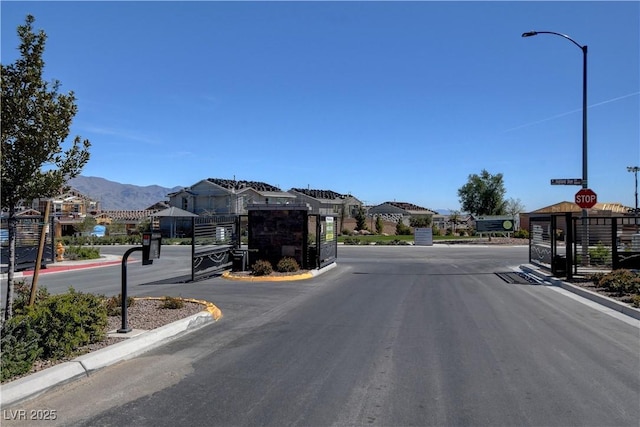 view of road with a gate, curbs, a gated entry, and a mountain view