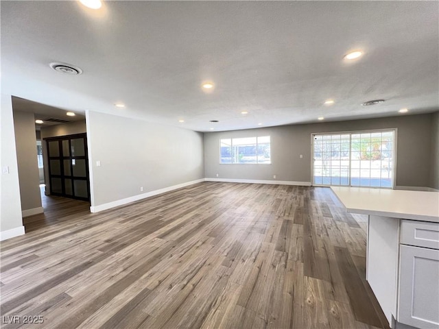 unfurnished living room featuring recessed lighting, visible vents, baseboards, and wood finished floors