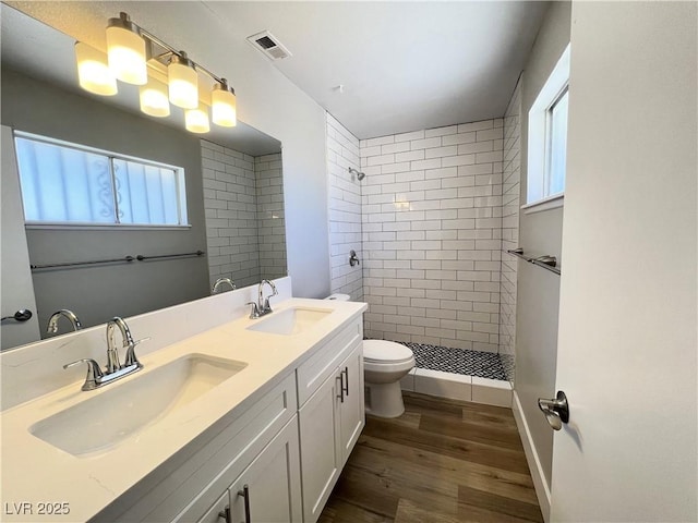 full bathroom with toilet, a stall shower, visible vents, and a sink