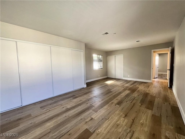 unfurnished bedroom with visible vents, baseboards, and wood finished floors