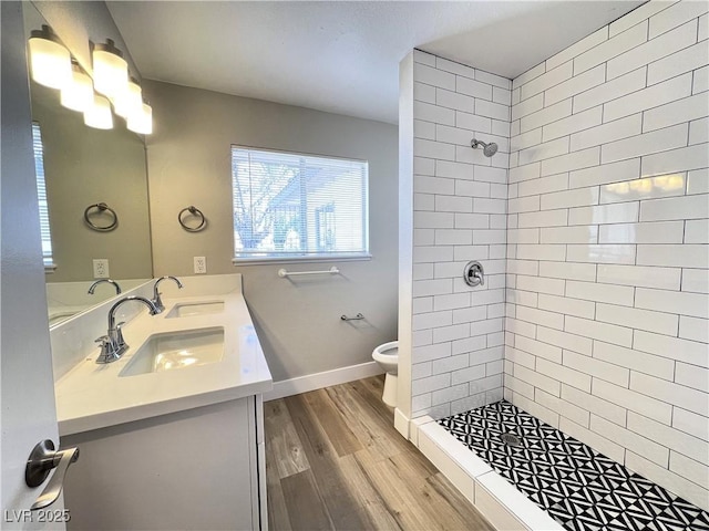 full bathroom with toilet, a sink, wood finished floors, a tile shower, and double vanity