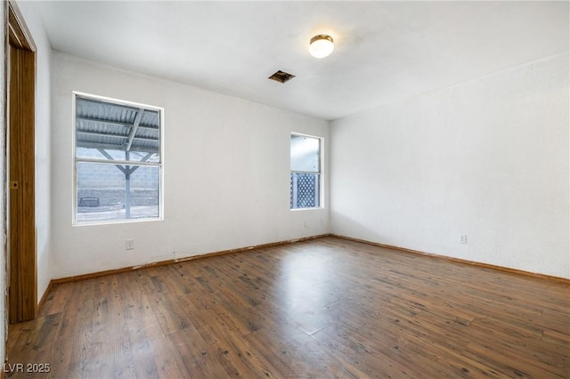 unfurnished room featuring hardwood / wood-style flooring, baseboards, and visible vents