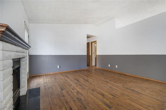 unfurnished living room featuring baseboards, vaulted ceiling, a fireplace, and hardwood / wood-style flooring