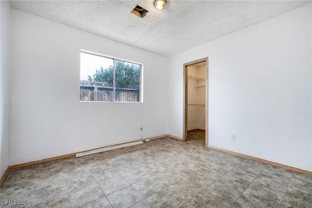 unfurnished room featuring a baseboard radiator, baseboards, and a textured ceiling