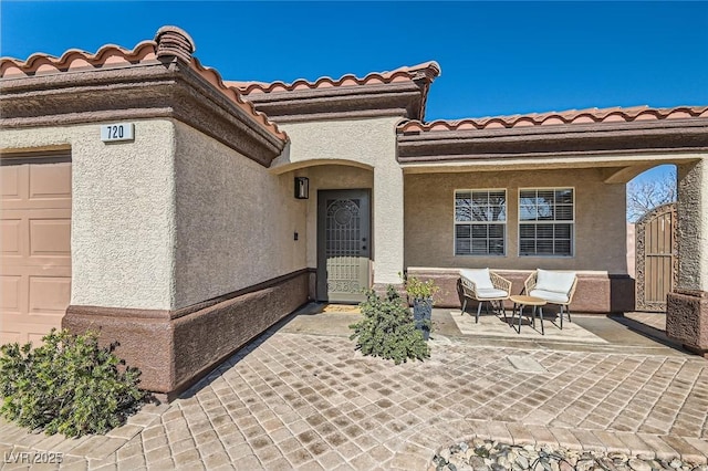 entrance to property with a garage, a tile roof, and stucco siding