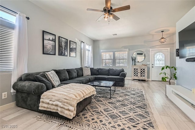 living room with a healthy amount of sunlight, light wood finished floors, ceiling fan, and baseboards