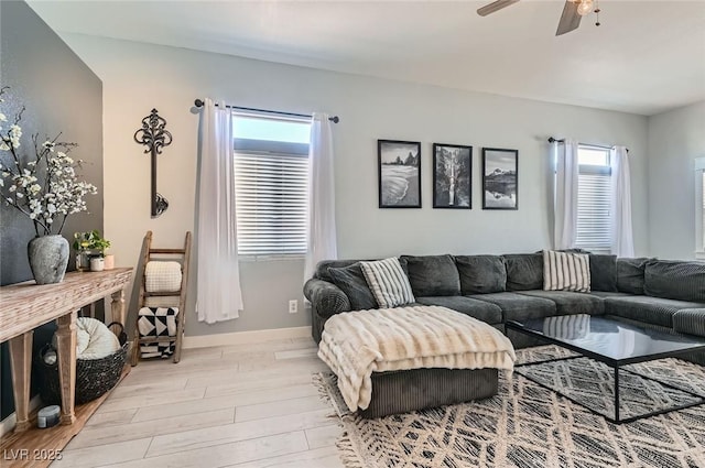 living room featuring a ceiling fan, baseboards, and wood finished floors