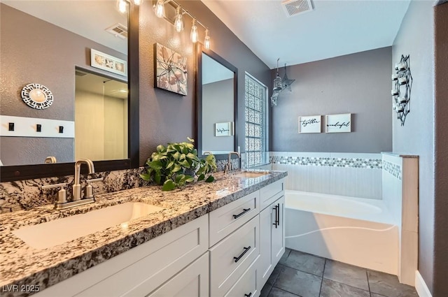 full bathroom featuring double vanity, a garden tub, visible vents, and a sink