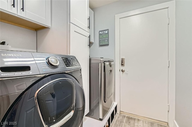 laundry room featuring cabinet space, washer and clothes dryer, and wood finished floors