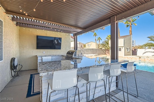 view of patio / terrace featuring a fenced in pool, a grill, fence, exterior kitchen, and outdoor wet bar