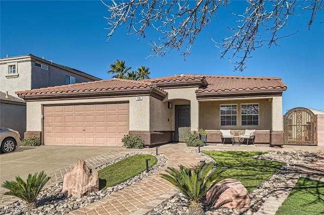 mediterranean / spanish-style house with a garage, concrete driveway, a tile roof, a gate, and stucco siding