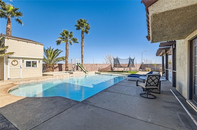 view of swimming pool featuring a trampoline, a fenced in pool, a patio, a fenced backyard, and an outdoor structure