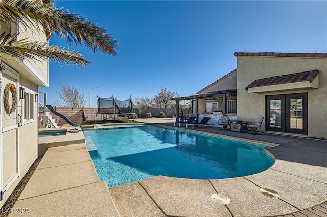 view of swimming pool with a trampoline, french doors, a patio area, a water slide, and a fenced backyard