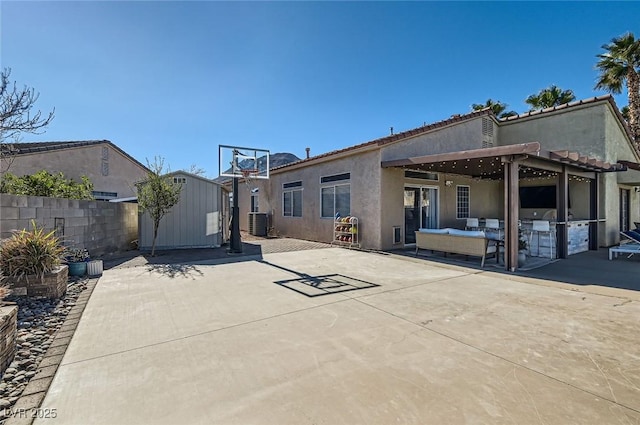 rear view of house with a patio, fence, a storage unit, an outdoor structure, and stucco siding