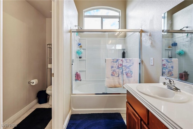 full bath featuring baseboards, toilet, shower / bath combination with glass door, tile patterned flooring, and vanity