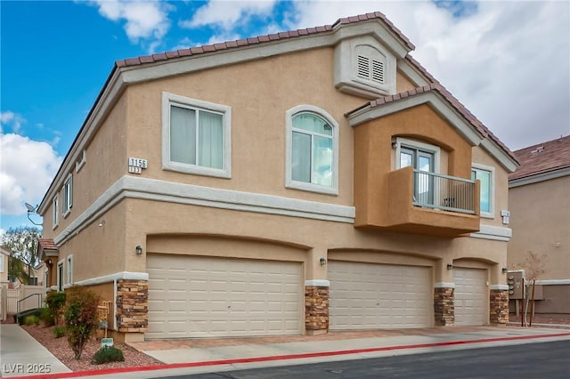 view of front of property featuring a garage, a balcony, stone siding, a tiled roof, and stucco siding