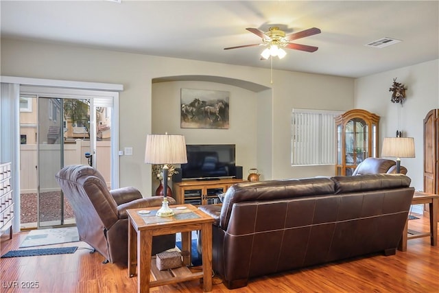 living room with a ceiling fan, visible vents, and wood finished floors