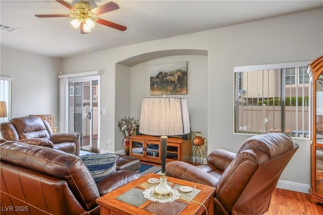 living room featuring baseboards, wood finished floors, visible vents, and a ceiling fan