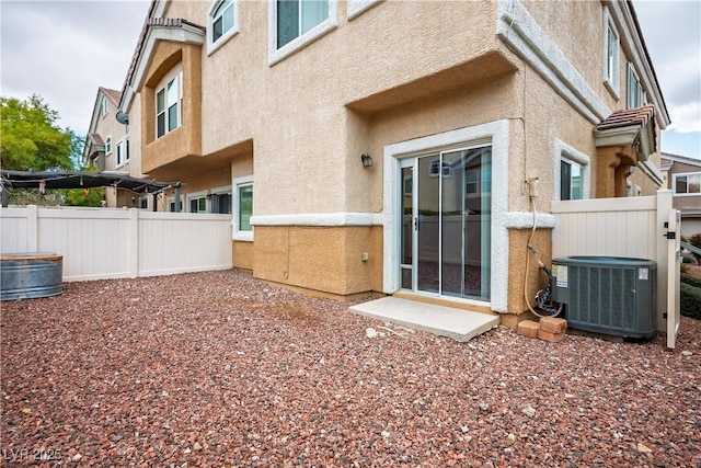 back of house featuring central AC unit, fence, and stucco siding