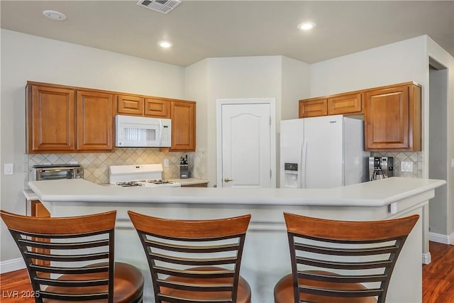 kitchen with white appliances, visible vents, a breakfast bar, and light countertops