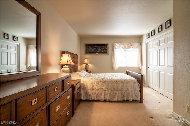 bedroom with baseboards, a closet, and light colored carpet