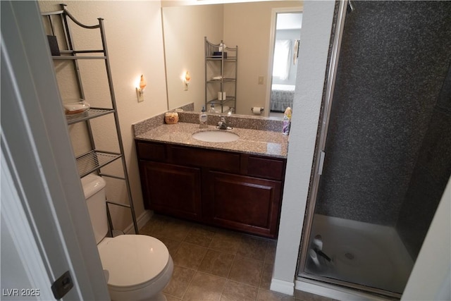 bathroom with a stall shower, vanity, toilet, and tile patterned floors