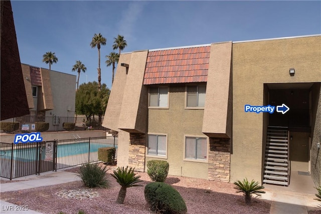 view of property with fence and a community pool