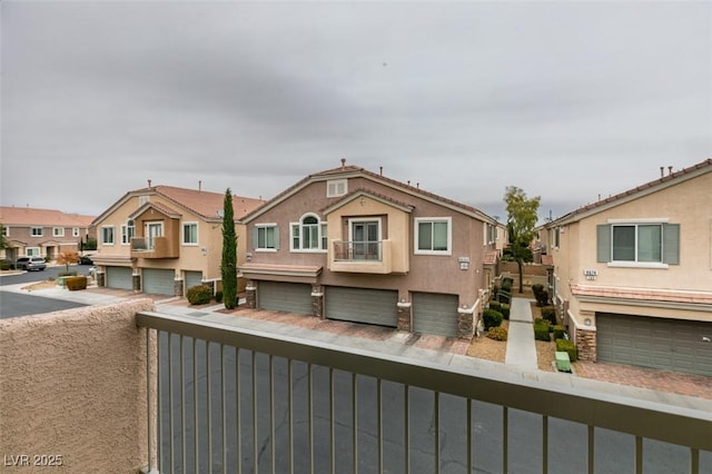 view of front of home with a garage, a balcony, a residential view, and stucco siding