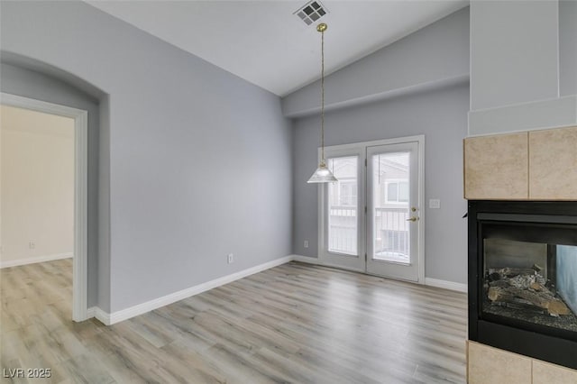 unfurnished living room featuring lofted ceiling, a fireplace, wood finished floors, visible vents, and baseboards