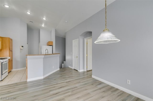 kitchen featuring light wood-type flooring, white appliances, decorative light fixtures, and baseboards