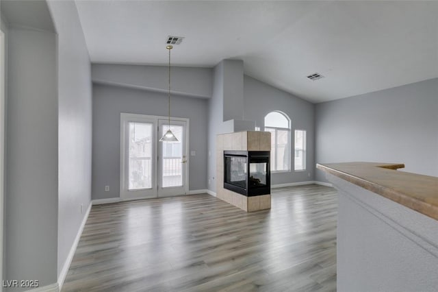 unfurnished living room with a fireplace, wood finished floors, visible vents, and baseboards