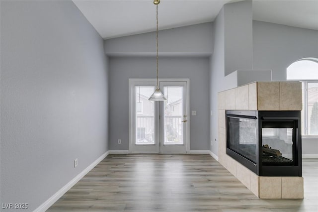 interior space featuring pendant lighting, a fireplace, wood finished floors, high vaulted ceiling, and baseboards