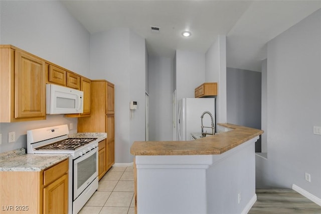 kitchen with light tile patterned floors, visible vents, white appliances, a peninsula, and baseboards