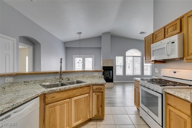 kitchen with lofted ceiling, a tile fireplace, white appliances, a sink, and visible vents