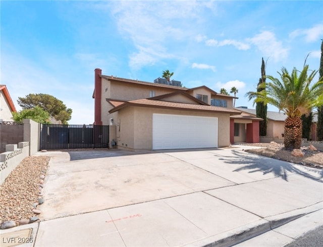 traditional-style house featuring driveway, fence, an attached garage, and stucco siding