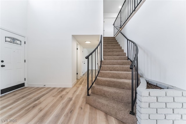 entrance foyer with a high ceiling, stairway, light wood-style flooring, and baseboards