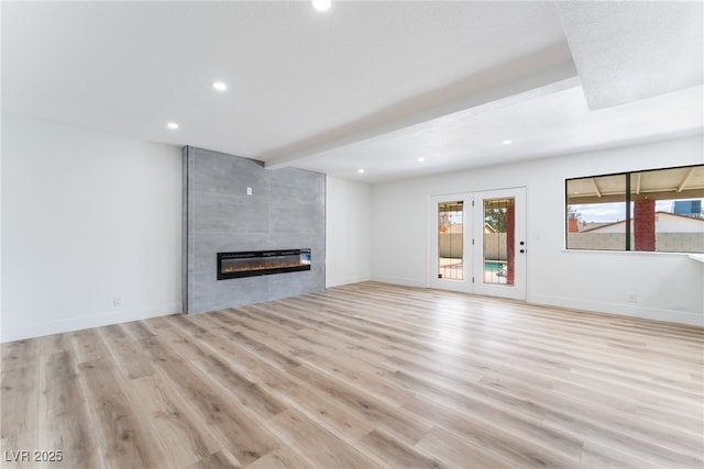 unfurnished living room featuring wood finished floors, recessed lighting, a tile fireplace, and baseboards