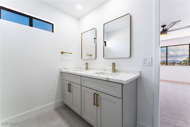 bathroom featuring double vanity, plenty of natural light, baseboards, and a sink