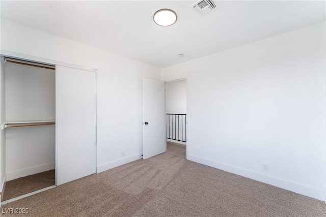 unfurnished bedroom with carpet, a closet, visible vents, and baseboards