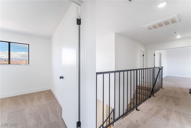 hall with carpet flooring, visible vents, and baseboards