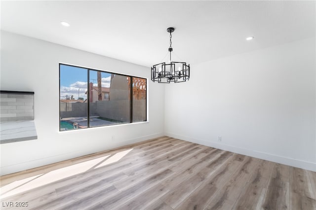 spare room featuring a chandelier, recessed lighting, baseboards, and wood finished floors