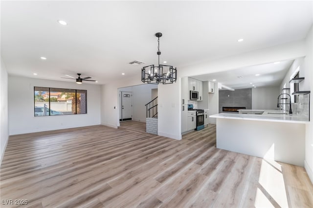 kitchen with a large fireplace, visible vents, appliances with stainless steel finishes, open floor plan, and white cabinetry