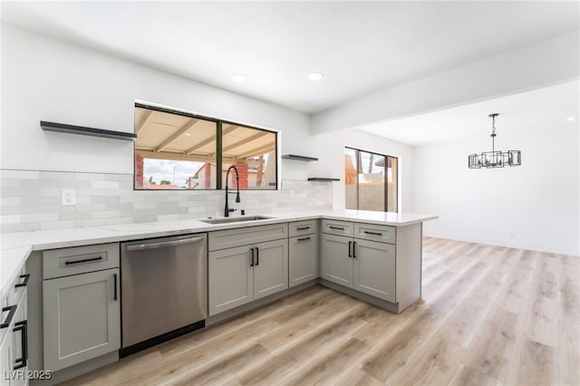 kitchen with gray cabinetry, a sink, stainless steel dishwasher, and open shelves