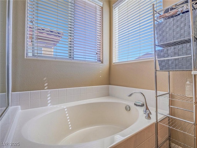 full bathroom featuring a textured wall and a bath