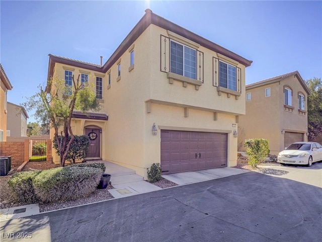 view of front of house with driveway, an attached garage, fence, and stucco siding