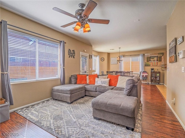 living room with ceiling fan, baseboards, and wood finished floors