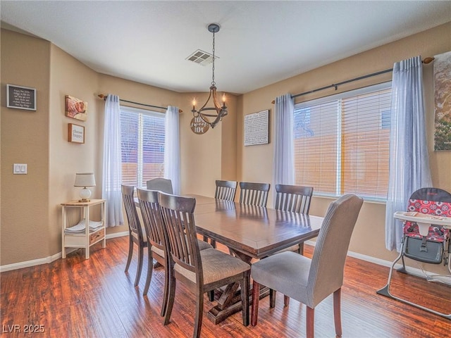 dining space featuring a chandelier, wood finished floors, visible vents, and baseboards