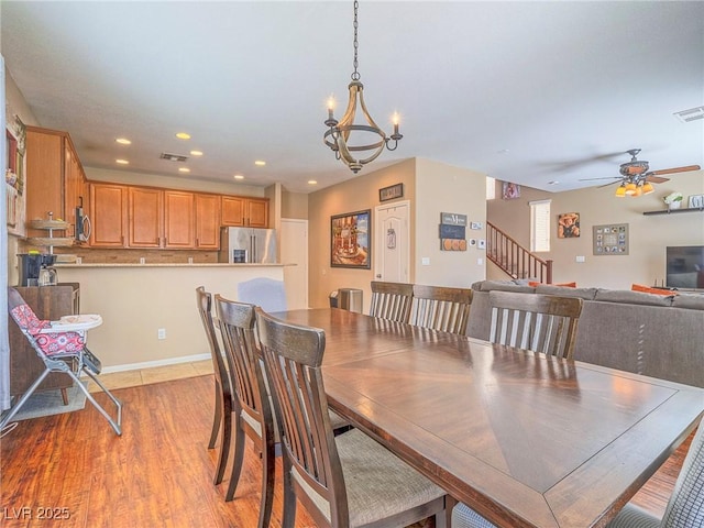 dining area featuring recessed lighting, visible vents, stairway, light wood-style floors, and ceiling fan with notable chandelier