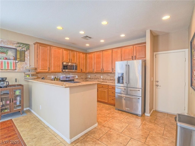 kitchen with recessed lighting, stainless steel appliances, a peninsula, visible vents, and decorative backsplash